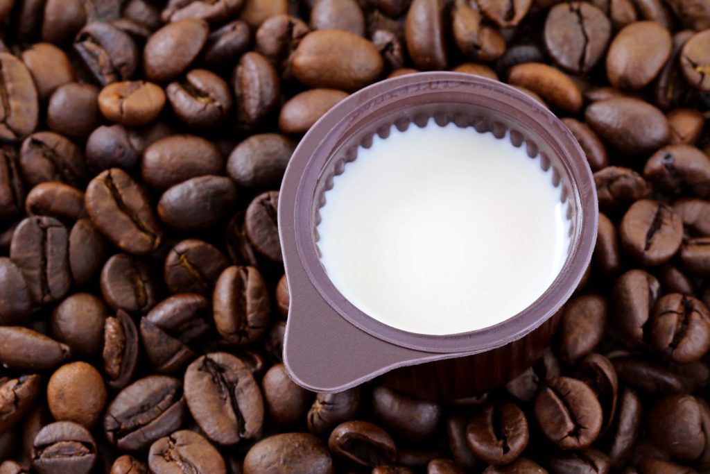 36854062 - a small cup of coffee creamer on coffee beans