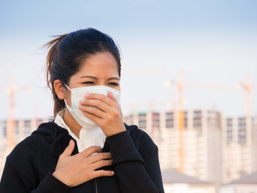 63643492 - asian woman wearing face mask and coughing by pollution